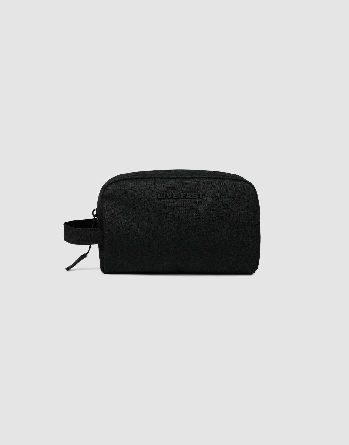 The LFDY Amenity Kit by LIVE FAST DIE YOUNG is a black polyester zip pouch with a side handle, "LIVE FAST" embossed on the front, a large zip compartment, and inner pockets, shown on a plain light gray background.