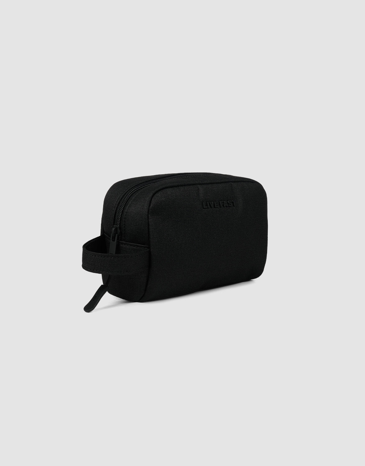 The LFDY Amenity Kit by LIVE FAST DIE YOUNG is a black rectangular toiletry bag made from durable polyester with a zipper closure, side handle, and large zip pocket, shown against a light gray background.
