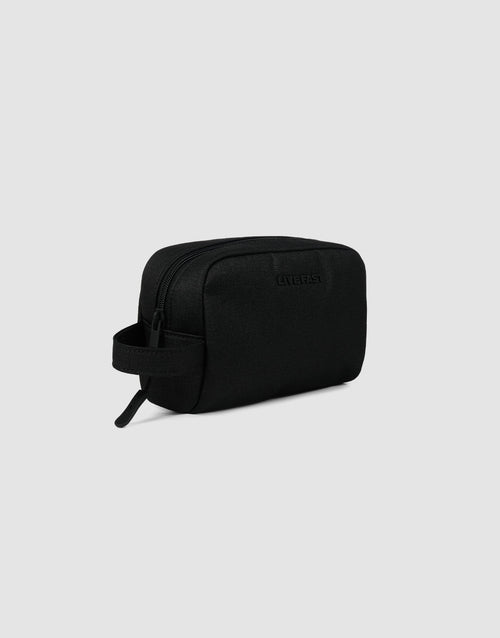 The LFDY Amenity Kit by LIVE FAST DIE YOUNG is a black rectangular toiletry bag made from durable polyester with a zipper closure, side handle, and large zip pocket, shown against a light gray background.