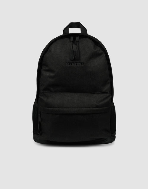 The LFDY Backpack by LIVE FAST DIE YOUNG is a plain black rucksack (19L) with a front zip pocket, small top handle, embossed "LIVEFAST" logo, and verstellbare Schultergurte, shown on a light gray background.