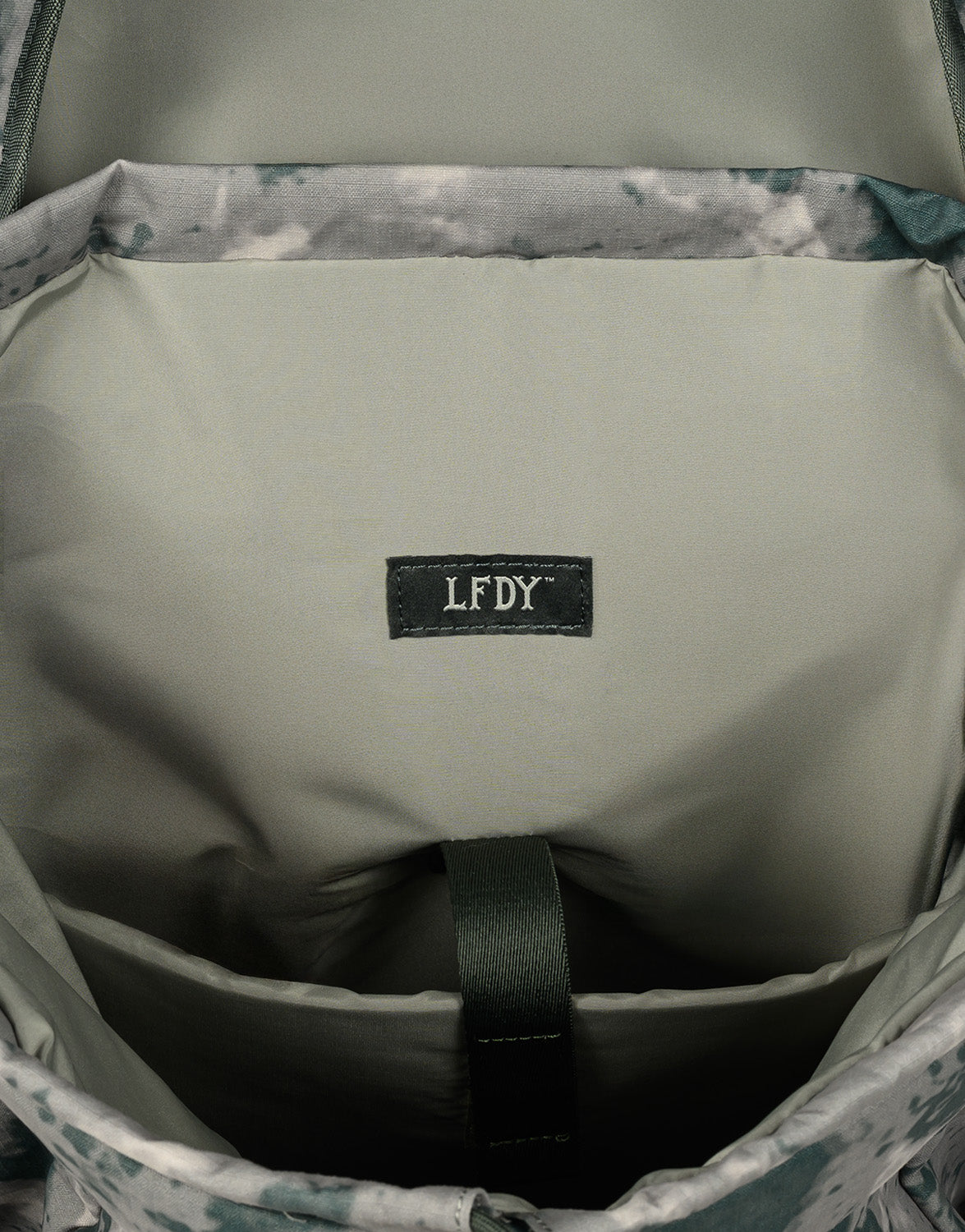Close-up of the inner compartment of the LFDY Travel Backpack by LIVE FAST DIE YOUNG, showing a camouflage lining, fabric label with LFDY in white stitching, a green strap loop, and adjustable shoulder straps.