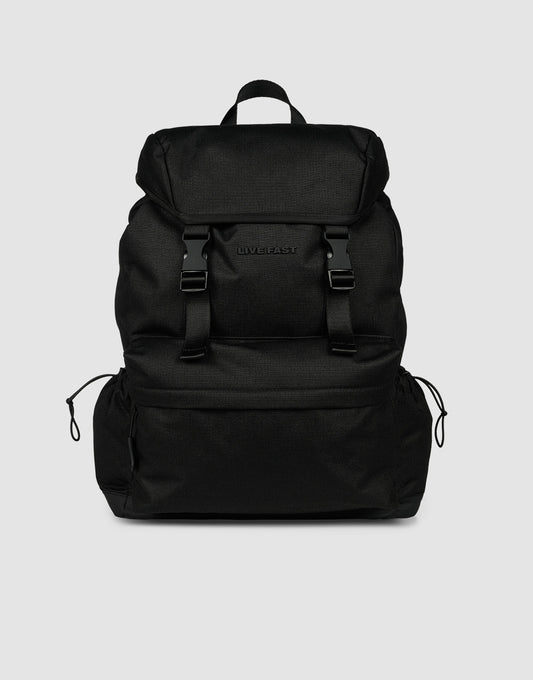 The LFDY Travel Backpack by LIVE FAST DIE YOUNG is a black 25L rucksack featuring adjustable shoulder straps, a top flap, two front buckles, side drawstring pockets, and a top handle, shown against a plain light gray background.