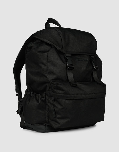 The LFDY Travel Backpack by LIVE FAST DIE YOUNG is a black, 25L rucksack with a top flap and two buckles, front zippered pocket, side pockets, and adjustable shoulder straps, shown on a plain light gray background.