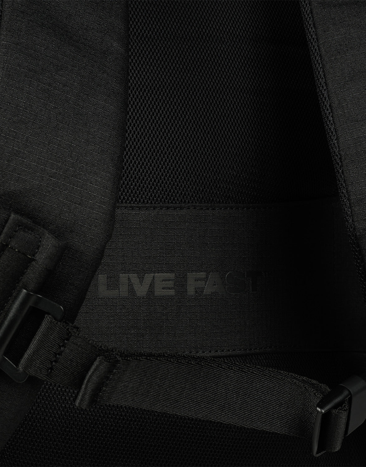 Close-up of the LFDY Travel Backpack (25L) by LIVE FAST DIE YOUNG, featuring padded mesh fabric, adjustable shoulder straps, a back strap, and the phrase LIVE FAST in subtle dark lettering.