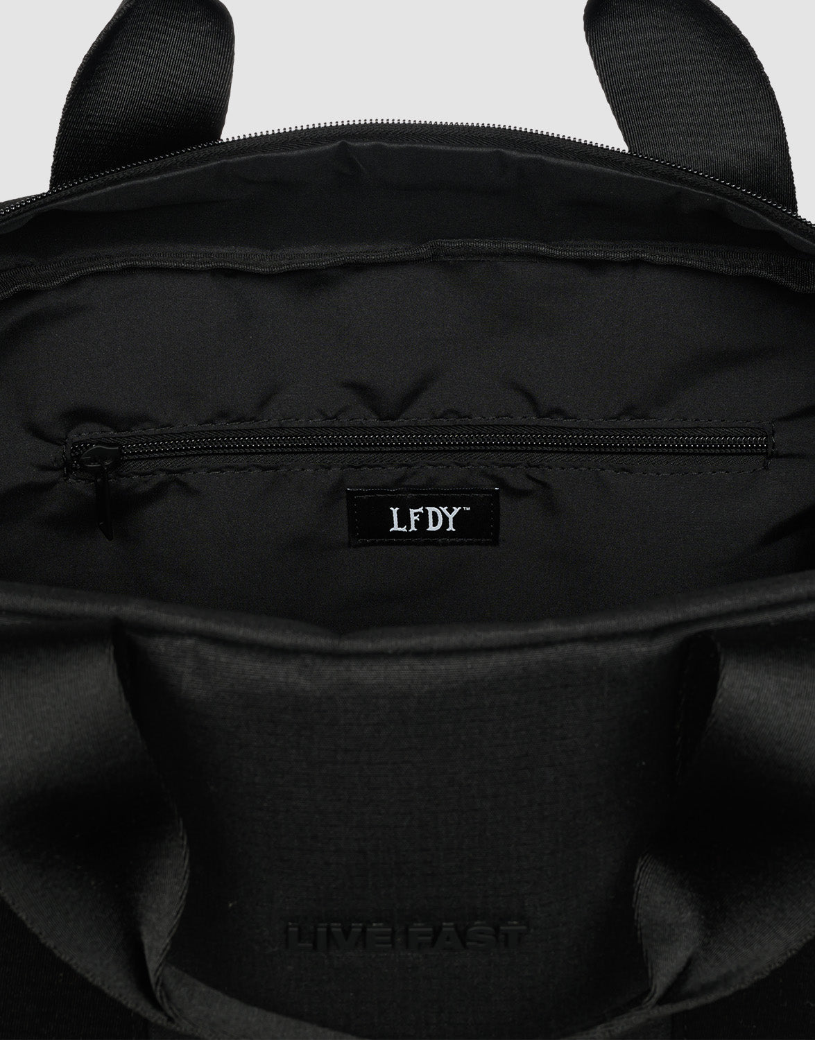 Close-up of the black LFDY Weekender 50’s interior shows a zippered pocket with an LFDY label and LIVE FAST embossed on the outer flap. Brand: LIVE FAST DIE YOUNG.