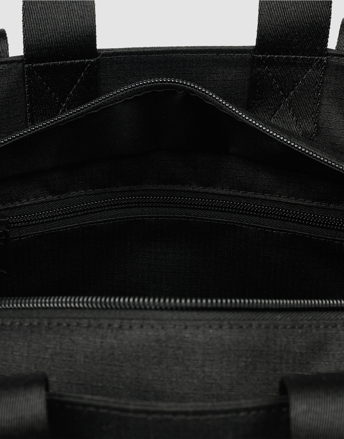 Close-up of the inside of the LFDY Utility Bag by LIVE FAST DIE YOUNG, featuring a zippered pocket, stitched seams, sturdy polyester fabric, two handles, and a großes Fach that emphasizes its spacious interior.