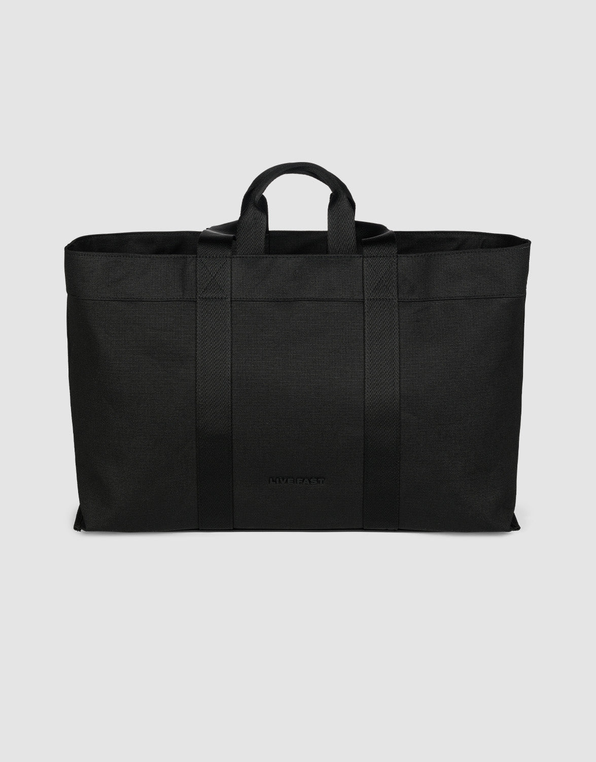 The LFDY Utility Bag by LIVE FAST DIE YOUNG is a large black tote made of durable polyester, featuring two short handles, two shoulder straps, and a spacious main compartment. Minimalist in design, it's shown upright against a light gray background.