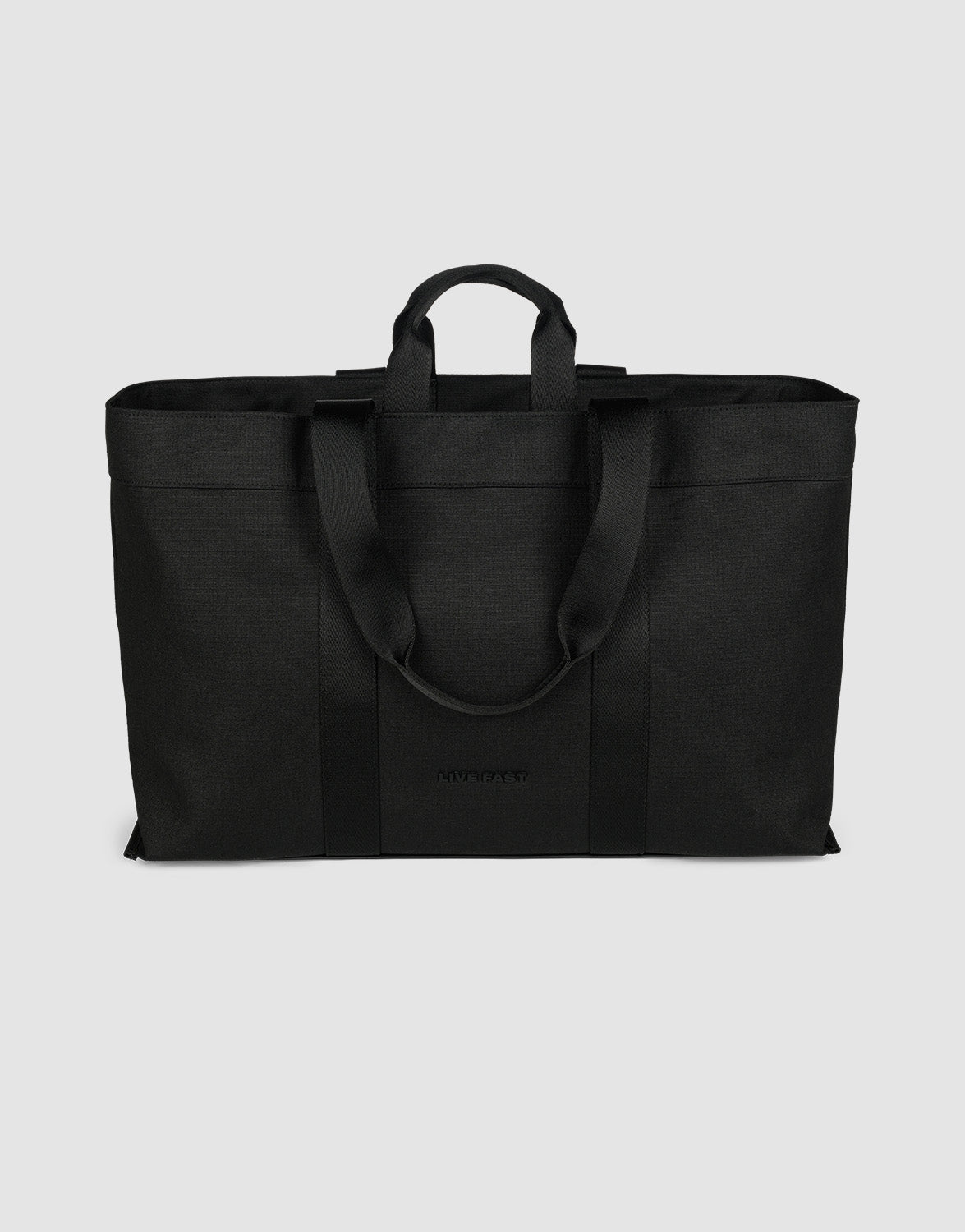 The LFDY Utility Bag by LIVE FAST DIE YOUNG is a large black tote with two short handles, two long shoulder straps, a spacious main compartment, and durable polyester construction, shown against a plain light gray background.