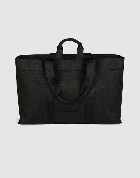 The LFDY Utility Bag by LIVE FAST DIE YOUNG is a large black tote with two short handles, two long shoulder straps, a spacious main compartment, and durable polyester construction, shown against a plain light gray background.