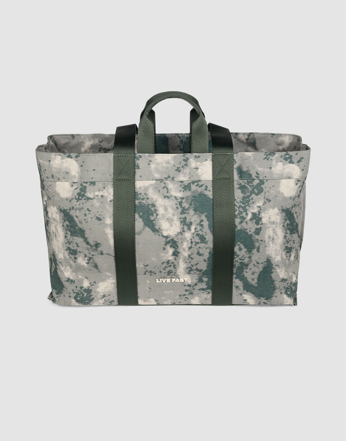 The LFDY Utility Bag by LIVE FAST DIE YOUNG is a rectangular tote with green and gray camouflage, dark green straps, and "LIVE FAST" printed at the bottom. It features a spacious main compartment. Shown on a plain light background.