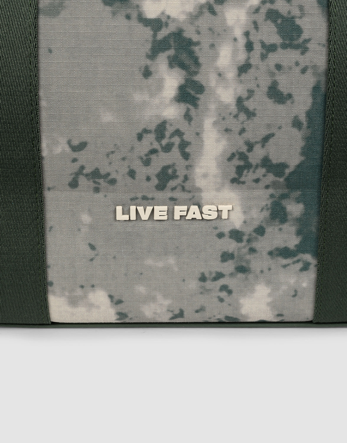 A close-up of the LFDY Utility Bag by LIVE FAST DIE YOUNG shows camouflage fabric with LIVE FAST in bold white letters and sturdy Tragegurte for easy carrying.