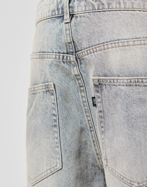 Close-up of the back of LFDY Baggy Denim, featuring a light-wash finish, baggy fit, two back pockets, faded fabric details, visible stitching, and a small black and white flag label on the seam near the right pocket.