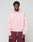 A person faces forward in a light pink LIVE FAST DIE YOUNG Basic Evidence Hooded Zip with an oversize fit and front pockets, paired with maroon pants, against a plain light gray background.