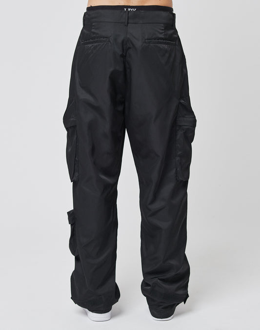 A person wears LIVE FAST DIE YOUNG Nylon Cargo pants in black with a regular fit, adjustable features, and multiple pockets. Viewed from the back, only the lower torso and legs show against a plain white background.