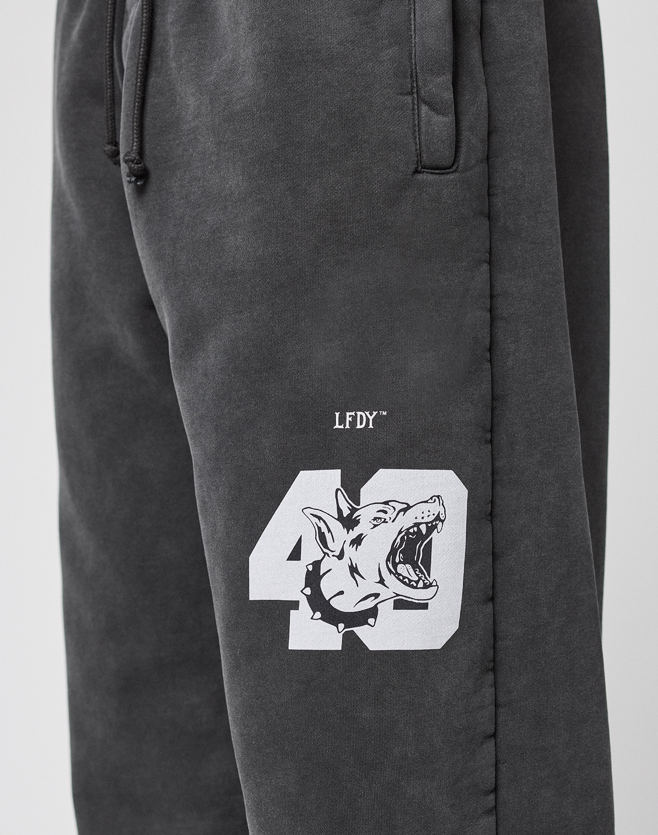 The LFDY 40 Wide Cuff Jogger by LIVE FAST DIE YOUNG are black oversize-fit sweatpants in soft cotton with side pockets, a white 40 and roaring wolf graphic, barbed wire accents, and LFDY text above the number on the left thigh.