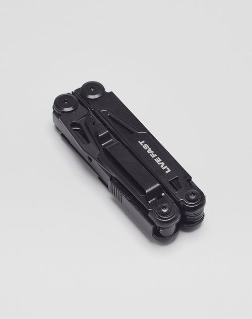 A black Live Fast Multifunction Tool aus Edelstahl mit mehreren faltbaren Werkzeugen ist geschlossen auf weißem Grund zu sehen. Der Markenname LIVE FAST DIE YOUNG ist in Weiß an der Seite aufgedruckt.