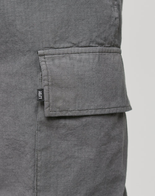 Close-up of a gray ripstop fabric Wide Cargo pocket with a flap, featuring a small black LIVE FAST DIE YOUNG tag sewn into the side seam.