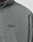 Close-up of a person in the LIVE FAST DIE YOUNG LFDY Light Halfzip, featuring gray satin fabric and tonal LfdY™ embroidery on the chest. The Oversize Fit highlights a relaxed silhouette with only the neck, shoulder, and upper chest shown.