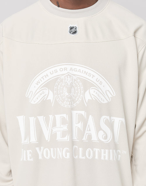 A person wearing the LIVE FAST DIE YOUNG LFDY Hockey Jersey, featuring a light color, “LIVE FAST DIE YOUNG CLOTHING” text, a circular emblem reading “WITH US OR AGAINST US” and “LIVING FASTER,” with a visible pendant necklace at the collar.