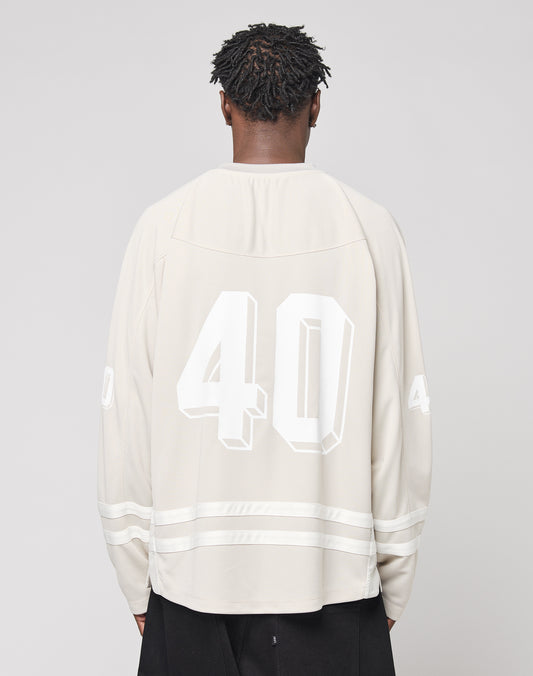 A person with short, twisted hair faces away, wearing an oversize light beige LFDY Hockey Jersey by LIVE FAST DIE YOUNG with the number 40 on the back and sleeves. The background is plain, light gray.