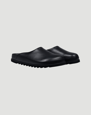 The LFDY Mules by LIVE FAST DIE YOUNG are black slip-on clogs with closed toes, textured PU Sohle, and schwarze Innenmaterial, shown on a plain light gray background.
