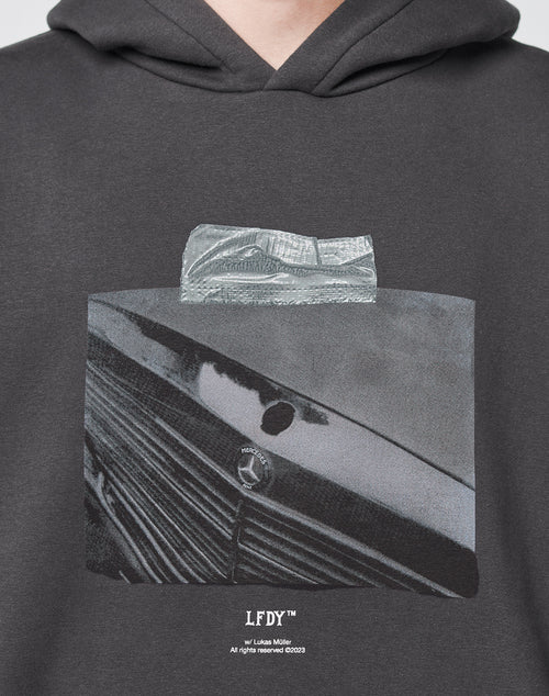 A close-up of the Benz Hooded by LIVE FAST DIE YOUNG, an oversized dark hoodie featuring a black-and-white vintage car grille and emblem front print, overlaid with a tape graphic and LFDY plus copyright details at the bottom.