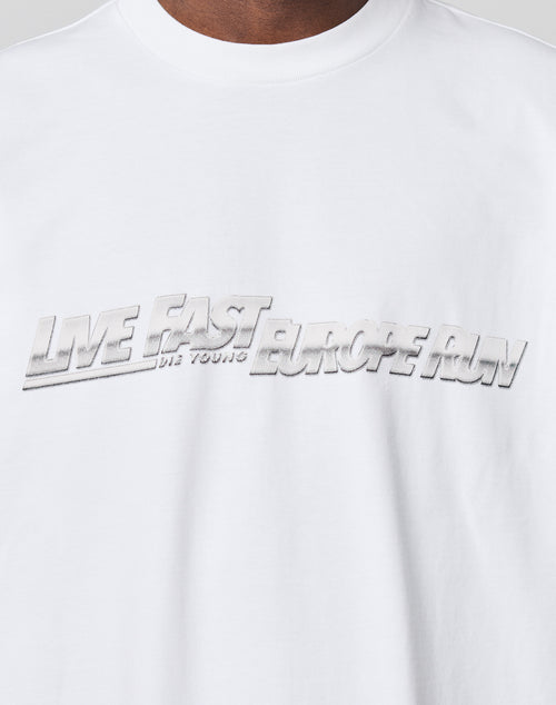 Close-up of the LIVE FAST DIE YOUNG LFDY Europe Run Tee, a white 100% cotton t-shirt with bold metallic silver 3D EUROPE RUN lettering across the chest and an oversized fit for a modern look.