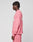 A person with short, twisted hair stands sideways against a plain light background, wearing an oversized pink Live Fast Boucle Sweater and matching pants from LIVE FAST DIE YOUNG.