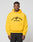 A man wearing a bright yellow LIVE FAST DIE YOUNG Live Fast Beware Hooded with LIVE FAST BEWARE and a fierce animal graphic on the front stands against a plain light gray background.