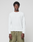 A man faces forward, arms relaxed, wearing the LIVE FAST DIE YOUNG Basic Waffle Longsleeve in white and olive green pants, against a plain background. The shirt features an oversize fit and flag-label detail.
