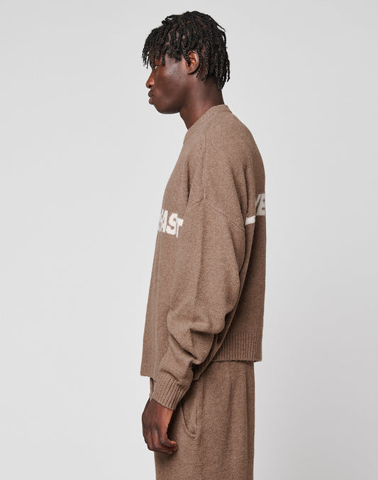 A person with short, textured hair stands in profile, wearing the LIVE FAST DIE YOUNG Live Fast Boucle Sweater in an oversize fit with matching pants against a plain light gray background.