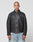 A person with a shaved head wears a black LIVE FAST DIE YOUNG LFDY Leather Jacket with zipper and light blue jeans, standing facing forward against a plain white background.
