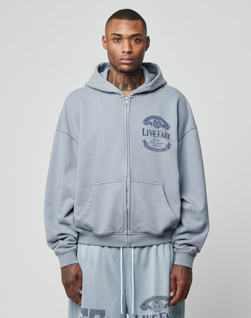 A man with short hair and neck tattoos faces forward, wearing the LIVE FAST DIE YOUNG LFDY 55 Hooded Zip in light gray and matching mesh shorts. He stands against a plain white background with a neutral expression.