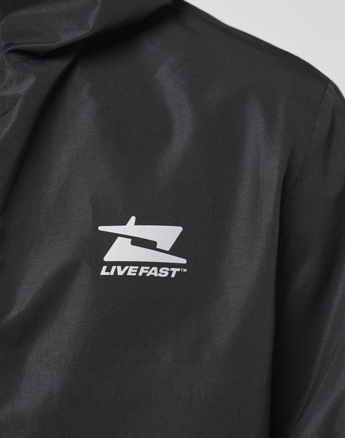 Close-up of the LIVE FAST DIE YOUNG Live Fast Performance Rain Jacket in black, featuring a white graphic logo and LIVE FAST™ on the chest. The image highlights the logo, shoulder area, and its Regular Fit for comfort.