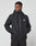A man wears the Live Fast Performance Rain Jacket by LIVE FAST DIE YOUNG, featuring a black zip-up design, regular fit, elastic cuffs, and a white chest logo, standing with hands in pockets and looking left against a plain light background.