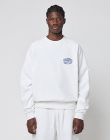 A person faces forward wearing a LIVE FAST DIE YOUNG LFDY Radiator Sweater in oversize white with matching pants. The Baumwolle Polyester sweater has a small blue LEARN TO LIVE graphic on the left chest. The background is plain light gray. | model