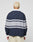 A person with short, bleached blonde hair faces away, wearing the LFDY Striped Polo by LIVE FAST DIE YOUNG—an oversize fit navy long-sleeve with light gray stripes—paired with cream pants, against a plain light background.