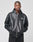 A person faces forward in a LIVE FAST DIE YOUNG Leather Hooded Jacket—an oversized black leather zip-up with pockets and a small white chest logo—set against a plain light gray background.