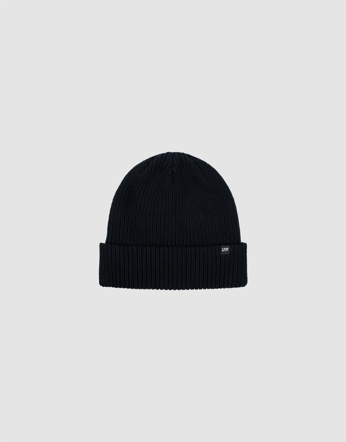 The LIVE FAST DIE YOUNG Double Rib Knit Beanie in black features a ribbed texture, folded brim, and a small black tag with white text, all displayed on a plain light gray background for a voluminous look.