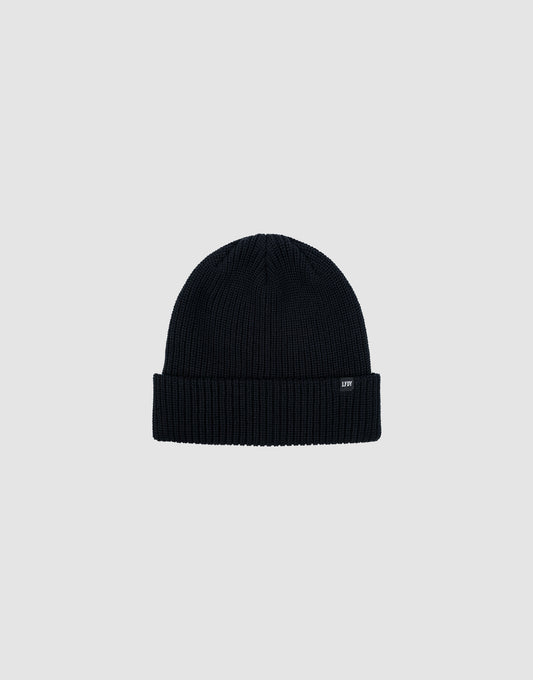 The LIVE FAST DIE YOUNG Double Rib Knit Beanie in black features a ribbed texture, folded brim, and a small black tag with white text, all displayed on a plain light gray background for a voluminous look.