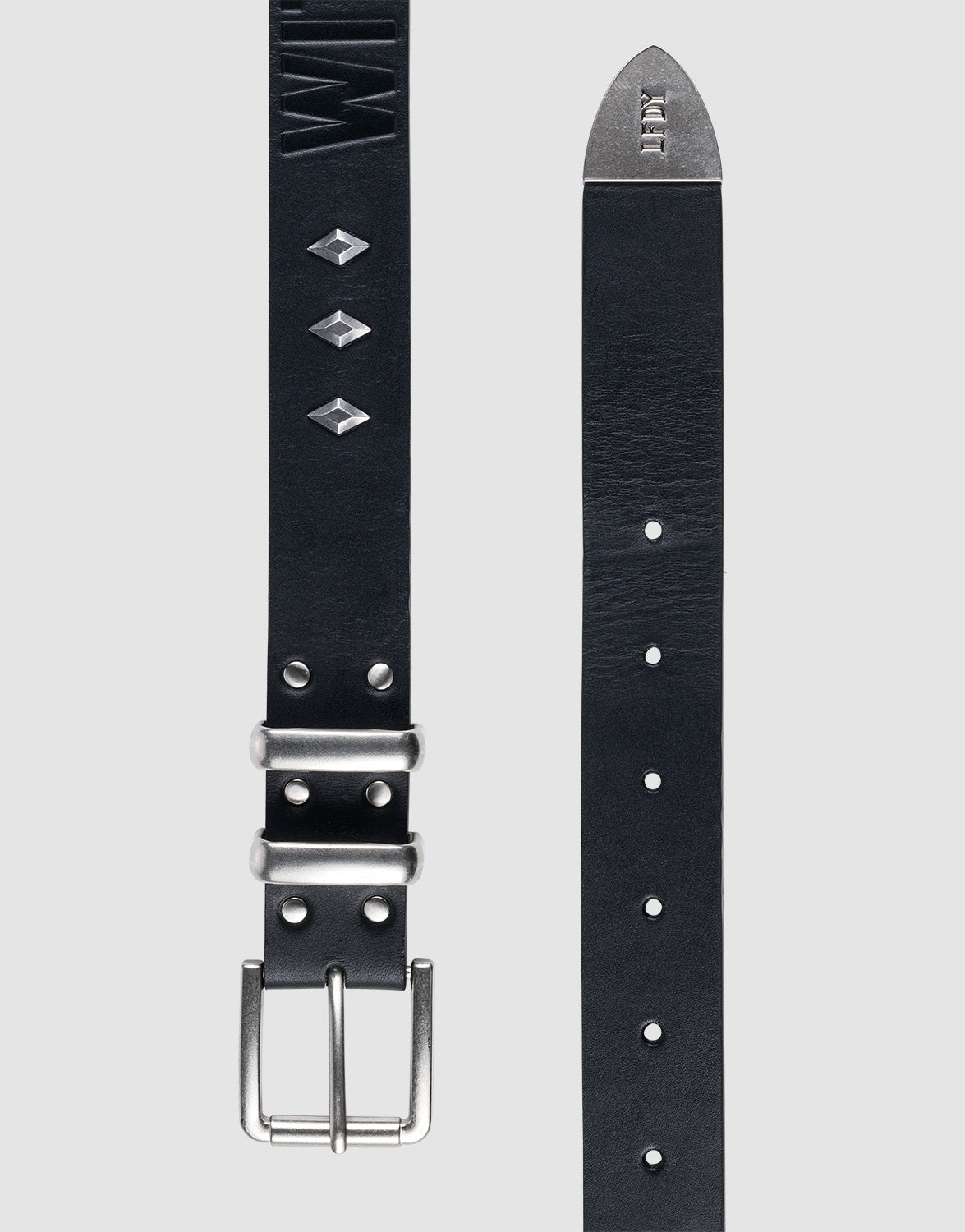 The LFDY Signature Belt by LIVE FAST DIE YOUNG features a black leather strap, silver buckle, diamond-shaped studs, embossed text near the buckle, and a pointed tip with metal accent—shown laid flat to reveal both buckle and tip details.