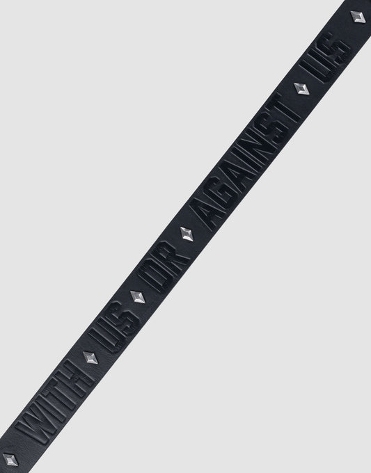 The LFDY Signature Belt by LIVE FAST DIE YOUNG features a black diagonal strip with raised "WITH US OR AGAINST US" text and diamond-shaped Nieten, all set against a plain light gray background.