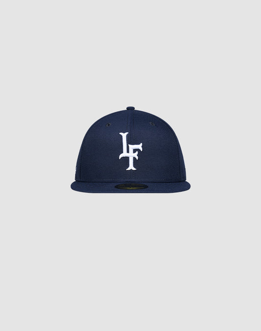 The LFDY x New Era 59Fifty Low Profile Paris cap by LIVE FAST DIE YOUNG features a navy blue design, flat brim, and white LF logo on the front, displayed against a plain light gray background.