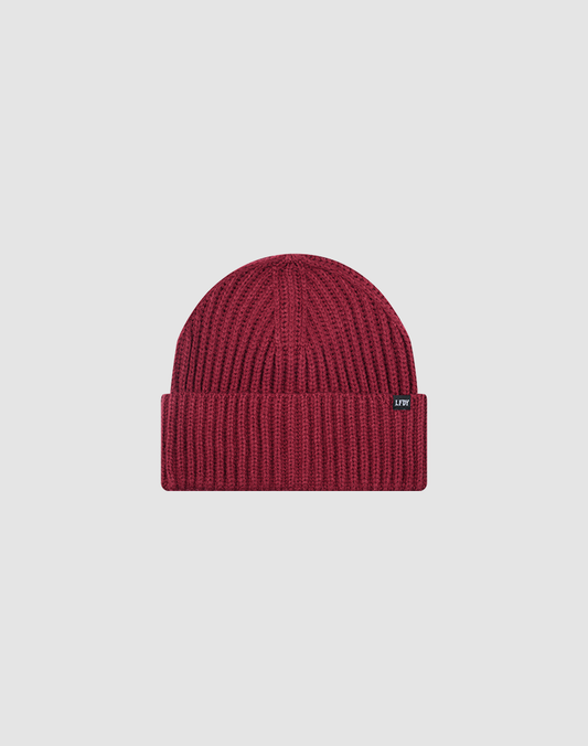 The LIVE FAST DIE YOUNG Rib Knit Beanie is maroon, one size, with a ribbed knit design, folded brim, and a small black rectangular flag-label on the side, shown against a plain light gray background.