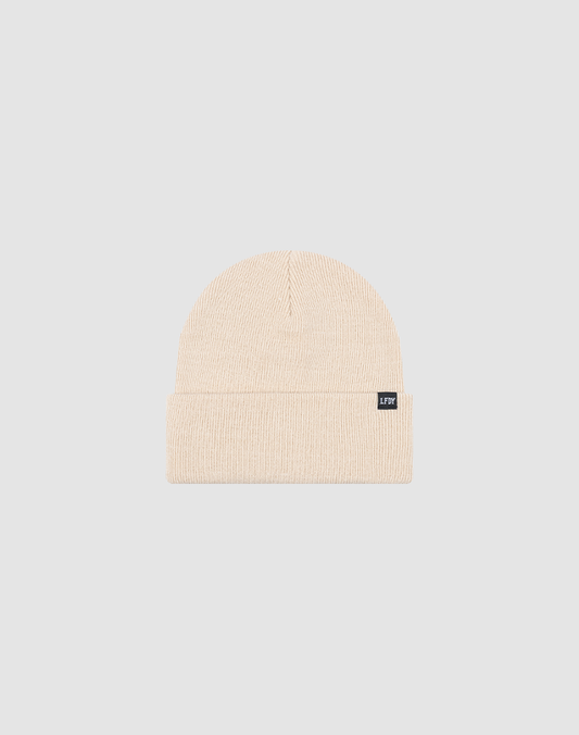 The LIVE FAST DIE YOUNG Basic Beanie in beige, One Size, features a folded brim and a small rectangular black Flag-Label on the cuff, shown on a light gray background.