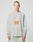 A person with short hair wears the LFDY Sports Longsleeve by LIVE FAST DIE YOUNG, featuring Raglan sleeves and an orange LIVE FAST graphic on light gray, paired with light-colored pants against a plain background.