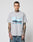 A man with tattoos and short hair wears the LFDY Crash Kid Tee by LIVE FAST DIE YOUNG, a light grey regular fit T-shirt featuring a car graphic and LIVE FAST text. He stands against a plain white background, looking at the camera.