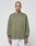 A person with a shaved head and neck tattoos wears the olive green LIVE FAST DIE YOUNG Basic Longsleeve with a white chest logo and light gray pants, standing against a plain light background.