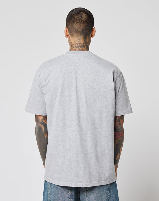 A person with short dark hair and visible tattoos stands with their back to the camera, wearing the light gray LIVE FAST DIE YOUNG LFDY Crash Kid Tee and blue jeans against a plain white background.
