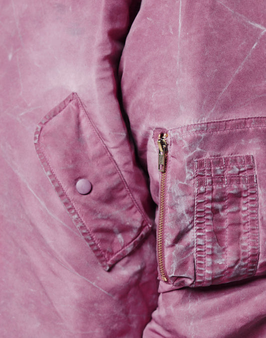 Close-up of the Washed Bomber Jacket by LIVE FAST DIE YOUNG, featuring a mauve hue, flap pocket, button, zippered sleeve pocket with Leder Puller, and vintage-washed textured fabric.